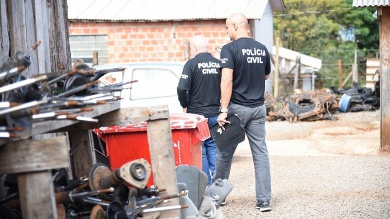 Foto que mostra dois policiais civis de costas, atuando em um desmanche irregular em Passo Fundo