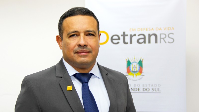 Foto do diretor técnico Fabio Pinheiro dos Santos em frente ao banner com o logo do DetranRS