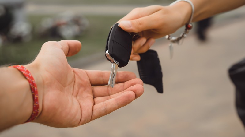 Duas mãos passando uma chave de carro uma para outra