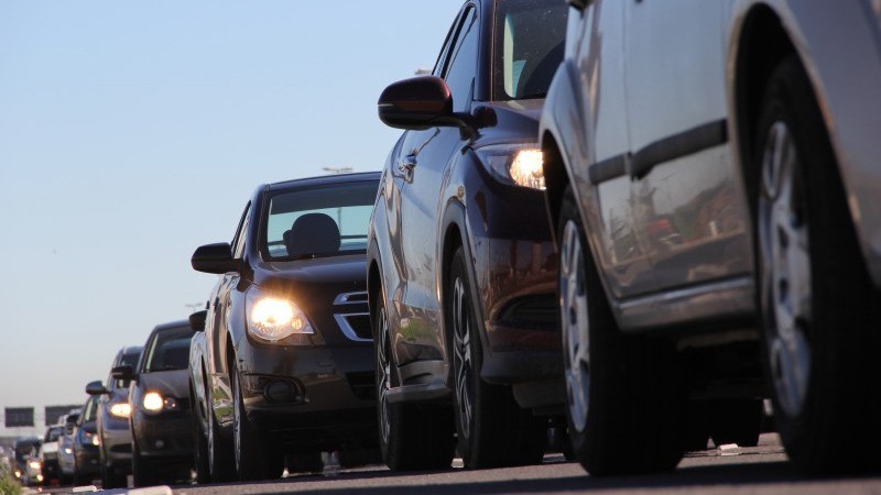 Veículos parados em fila em uma rodovia, durante o dia.