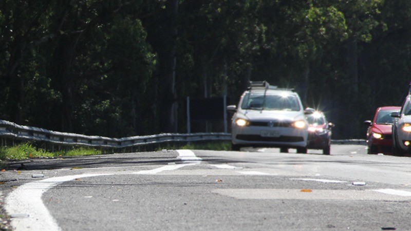 Veículos trafegando em rodovia com faróis ligados