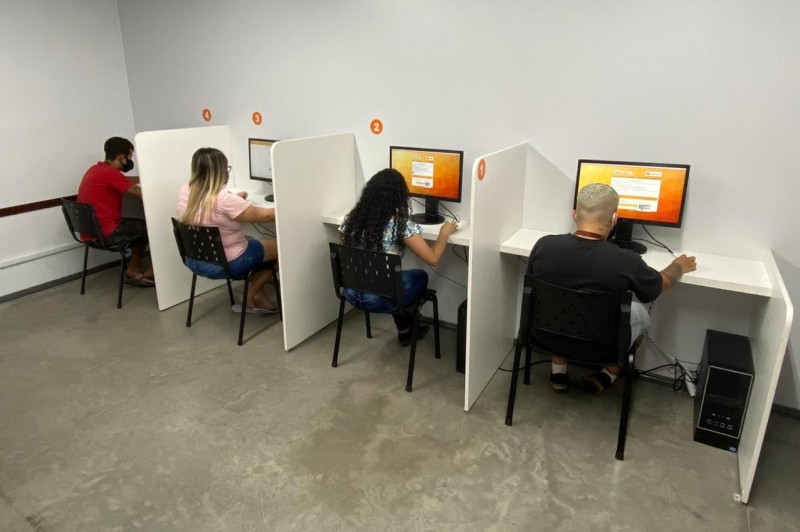 Quatro candidatos a habilitação estão sentados diante de comutadores, na sala de provas teóricas eletrônicas do CFC Soloscar, em Porto Alegre. Realizam prova teórica com a supervisão remota do fiscal da DetranRS.