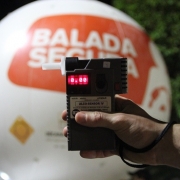 Com balão da fiscalização da Balada Segura ao fundo, um etilometro em primeiro plano mostra o resultado 0.00 no visor