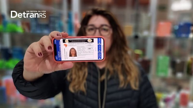 Mulher aponta a tela do celular para a câmera com o novo modelo de CNH