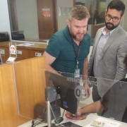 Foto horizontal colorida mostra atendente de CFC fazendo a coleta de digitais enquanto dois homens e uma mulher observam