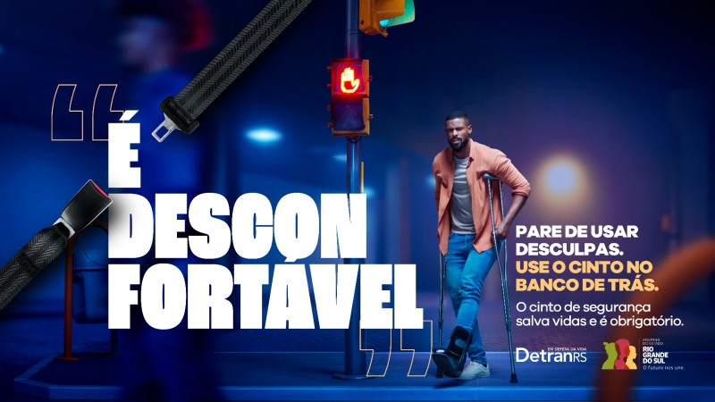 Foto horizontal colorida mostra homem de muletas com a frase É desconfortável entre aspas . Um cinto de segurança trespassa a imagem e na parte inferior à direita a assinatura da campanha: Pare de usar desculpas. Use o cinto no banco de trás. O cinto de segurança salva vidas e é obrigatório. DetranRS e Governo do Estado do RS