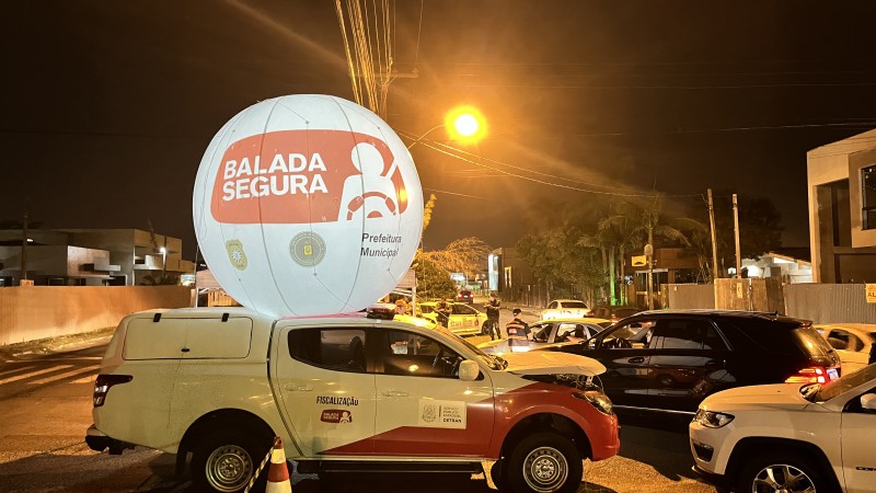 Caminhonete da Balada Segura com balão da operação iluminado e veículos estacionados