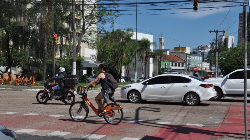 Foto horizontal colorida mostra cena de transito em Porto Alegre com ciclista em primeiro plano, carros e uma moto em segundo plano