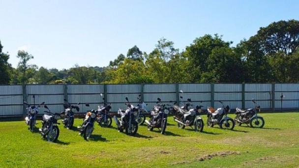 motos lado a lado sobre uma grama com um muro atrás