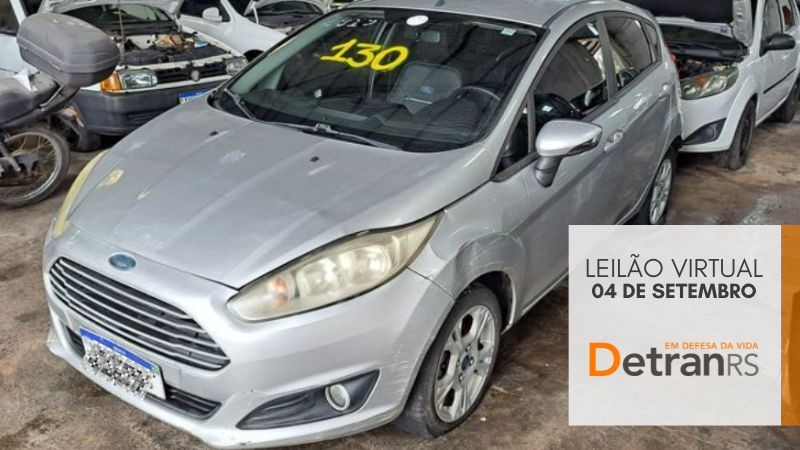 Ford Fiesta prata estacionado em depósito com outros veículos ao fundo e na lateral