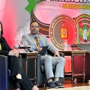 Rafael Mennet sentado, no palco do evento, ao lado de uma das palestrantes 