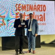 Em pá, lado a lado, Edir Domeneghini e Vilnei Sessim posam para foto mostrando a placa entregue como forma de homenagem