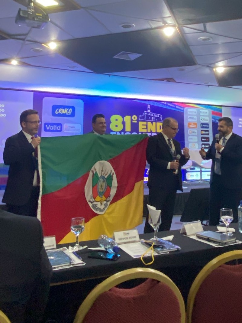 Marcelo Soletti, Vilnei Sessim (SindiCFC do RS) e DG Edir Domeneghini levaram a bandeira do RS para o palco do 81º END